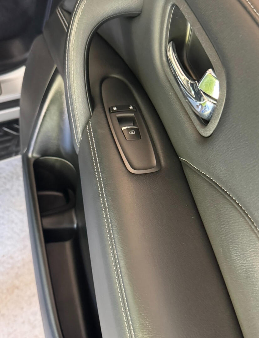 Clean black leather passenger-side door panel with chrome handle